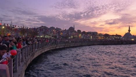 large crowd gathers at waterfront during sunset in istanbul