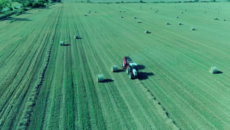 Tractor-Embalando-Pacas-Redondas-En-Bulgaria,-Julio-De-2018,-Drone-Filmando-A-Su-Alrededor