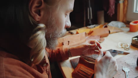 man preparing handmade cigarette at table in leather workshop