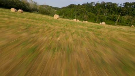 flying at high speed through hay bales in a farmland with an fpv drone at sunset