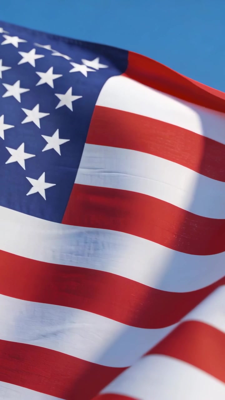 Video verticale: Bandiera americana che sventola con una leggera brezza all'aperto, mostrando stelle e strisce.