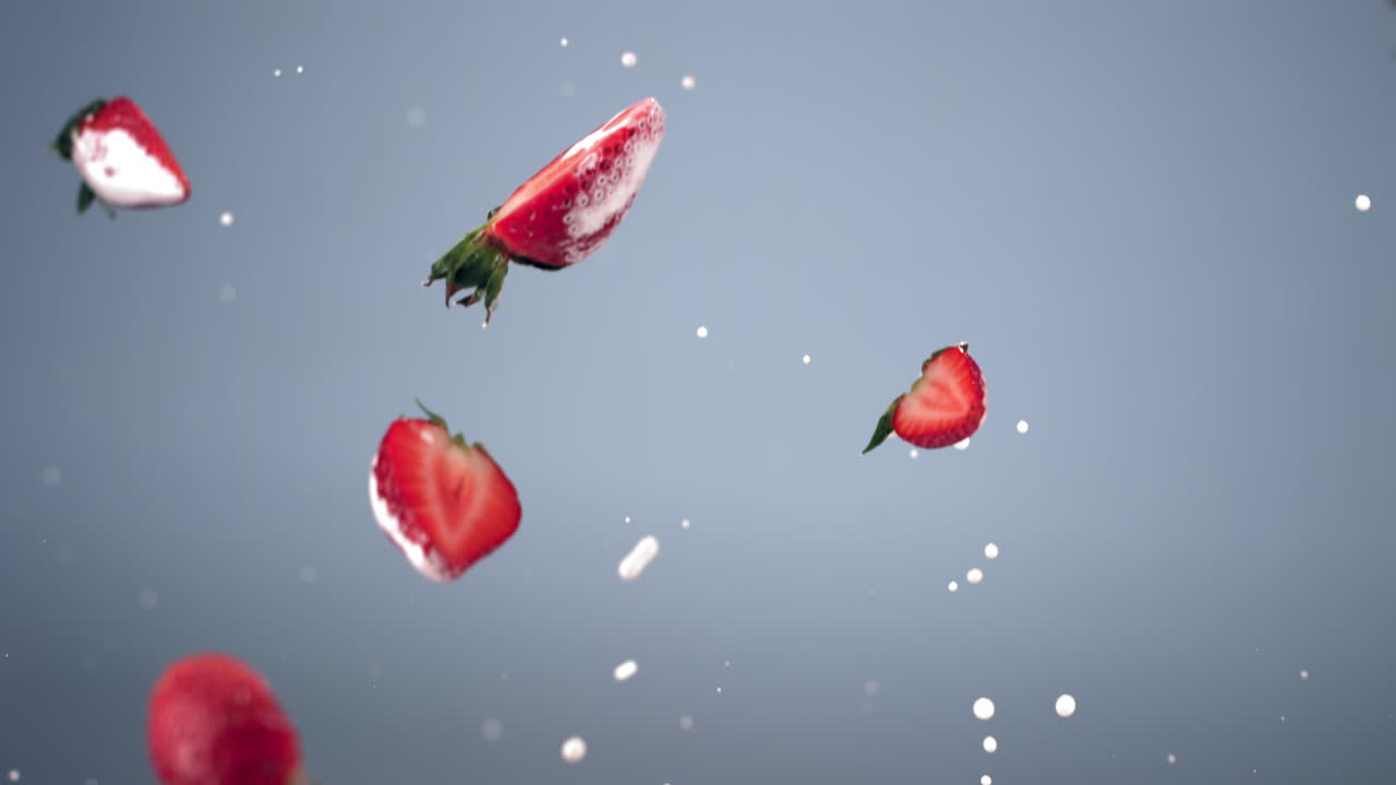 파란색 배경에 요거트 또는 우유 방울과 함께 날아가는 신선한 잘라진 딸기 슈퍼 느린 동작, 고속 카메라로 촬영, 420fps