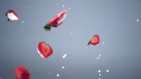 super slow motion shot of fresh sliced strawberries flying with yogurt or milk drops against blue background. shot with high speed camera, 420 fps