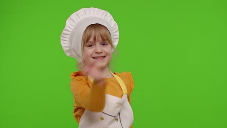 funny child girl kid dressed cook chef baker in apron and hat dancing, fooling around, making faces