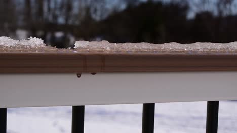 Winter-snow-and-ice-melting-and-dripping-off-top-of-deck-rail,-hydrology-snowmelt