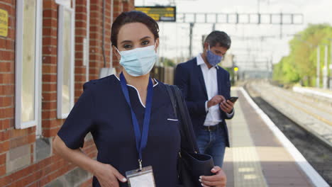portrait of nurse on railway platform wearing ppe face mask commuting to work during pandemic