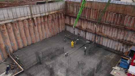 Panoramic-aerial-view-of-construction-workers-laying-cement-using-automatic-pump,-Israel