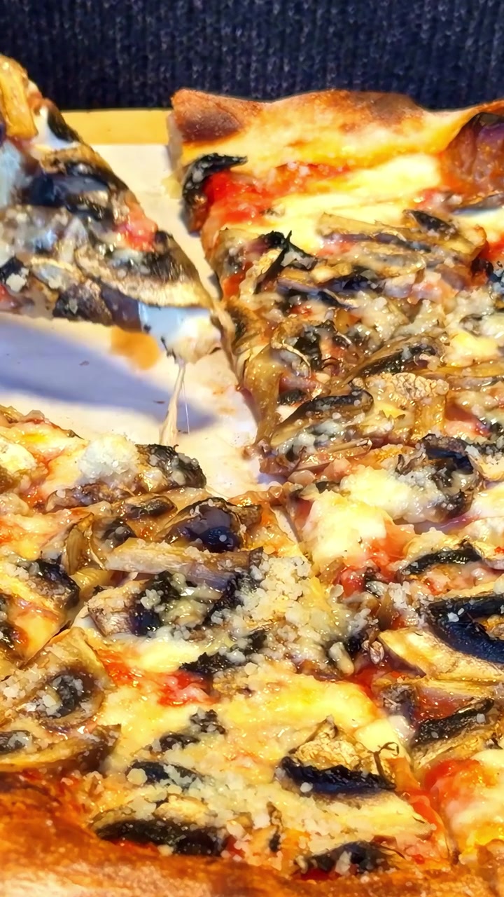 Mano che stacca una fetta di pizza ai frutti di mare con cozze, gamberetti, salsa di pomodoro e formaggio fuso, crosta cotta nel forno a legna, dettaglio in primo piano