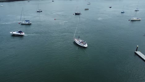 aerial view following luxury sailboat leaving harbour and travelling along scenic river estuary