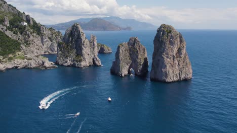 Boats-Exploring-Geological-Phenomenon-of-Faraglioni-Sea-Stack-Rock-Formations,-Aerial