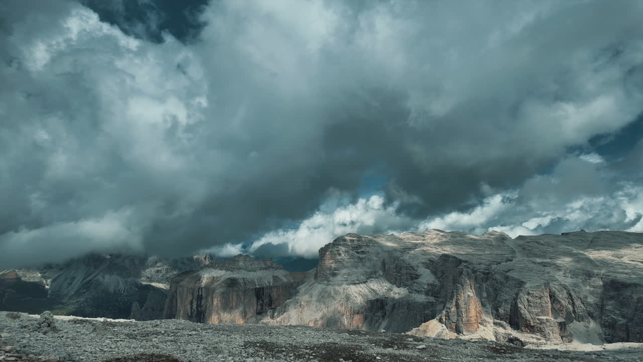 Dramatic timelapse revealing rapid cloud movement drifting across rugged rocky peaks of Dolomite mountain range in Italian alpine landscape