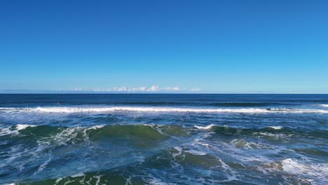 aerial footage of ocean waves along gold coast, australia. clear skies and vibrant blue water create a serene coastal scene