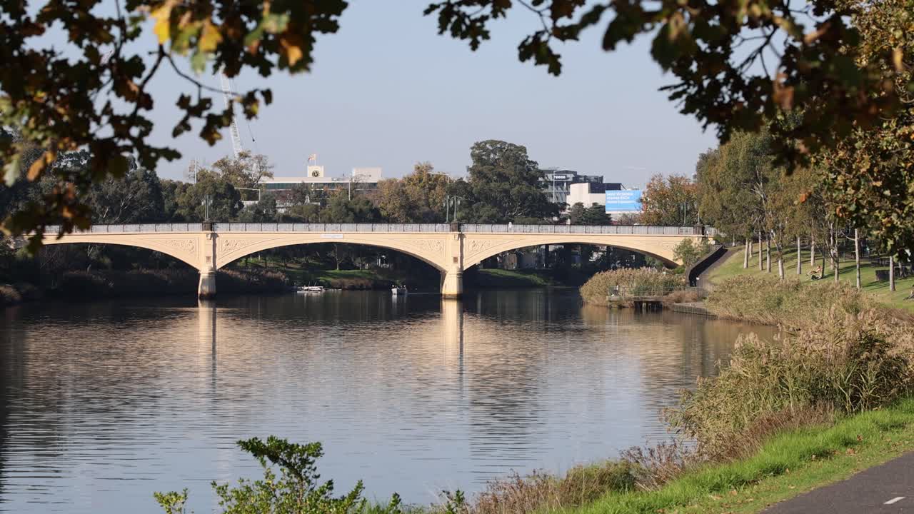 가을 잎으로 평온한 강을 가로지르는 다리