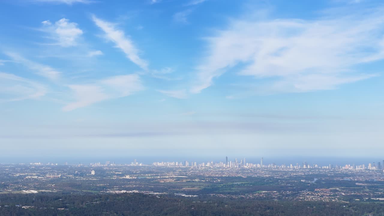 Smooth aerial pan from hinterland to city skyline under bright daylight and blue sky