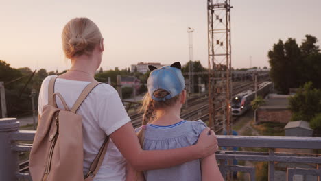 Una-Mujer-Y-Su-Hija-Se-Paran-En-Los-Puentes-Y-Miran-El-Tren-De-Abajo