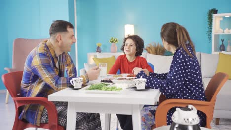 la alegre y animada familia está desayunando y el niño está haciendo reír a su familia.