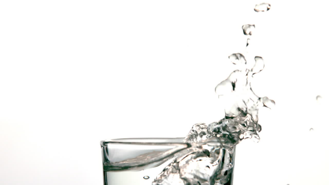 Cubetto di ghiaccio che cade nel bicchiere d'acqua