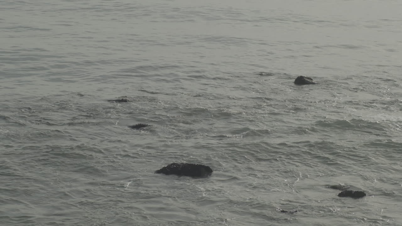 황금시간대에 해변 큰 바위 말리부의 야생 파도에 잠긴 바다 바위