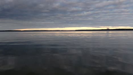 Drone-Moviéndose-Rápido-Sobre-Aguas-Tranquilas-En-Un-Lago-Durante-La-Puesta-De-Sol