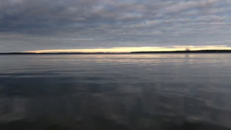 drone moviéndose rápido sobre aguas tranquilas en un lago durante la puesta de sol