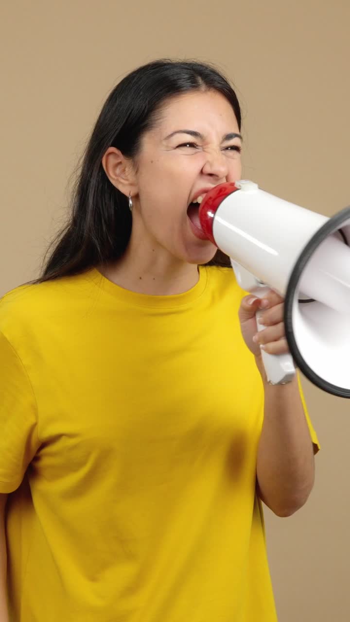 A woman passionately shouts into a megaphone, expressing strong emotions
