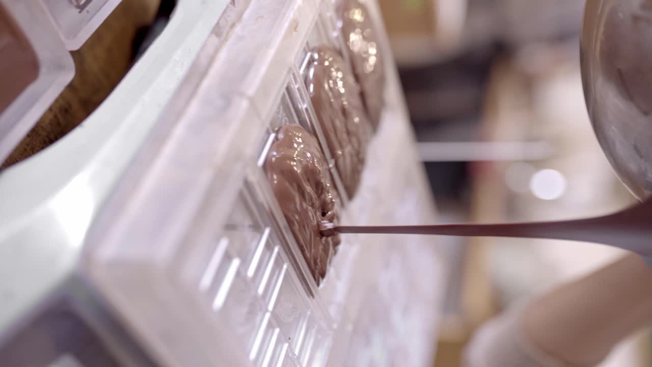 작물 초콜릿 제작자가 부 ⁇ 에서 녹은 초콜릿을 형태로  ⁇ 고 있습니다.