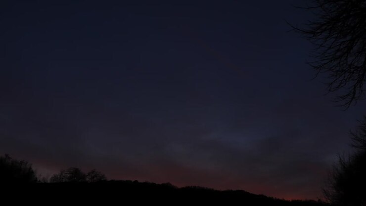 Time lapse del tramonto con nuvole e sagome di alberi