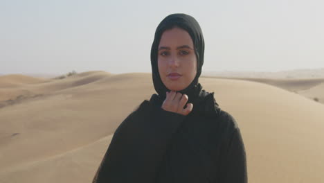 ritratto di una bella donna musulmana con hijab che guarda l'obbiettivo in un deserto ventoso