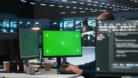 technician overseeing server room, running code on green screen computer