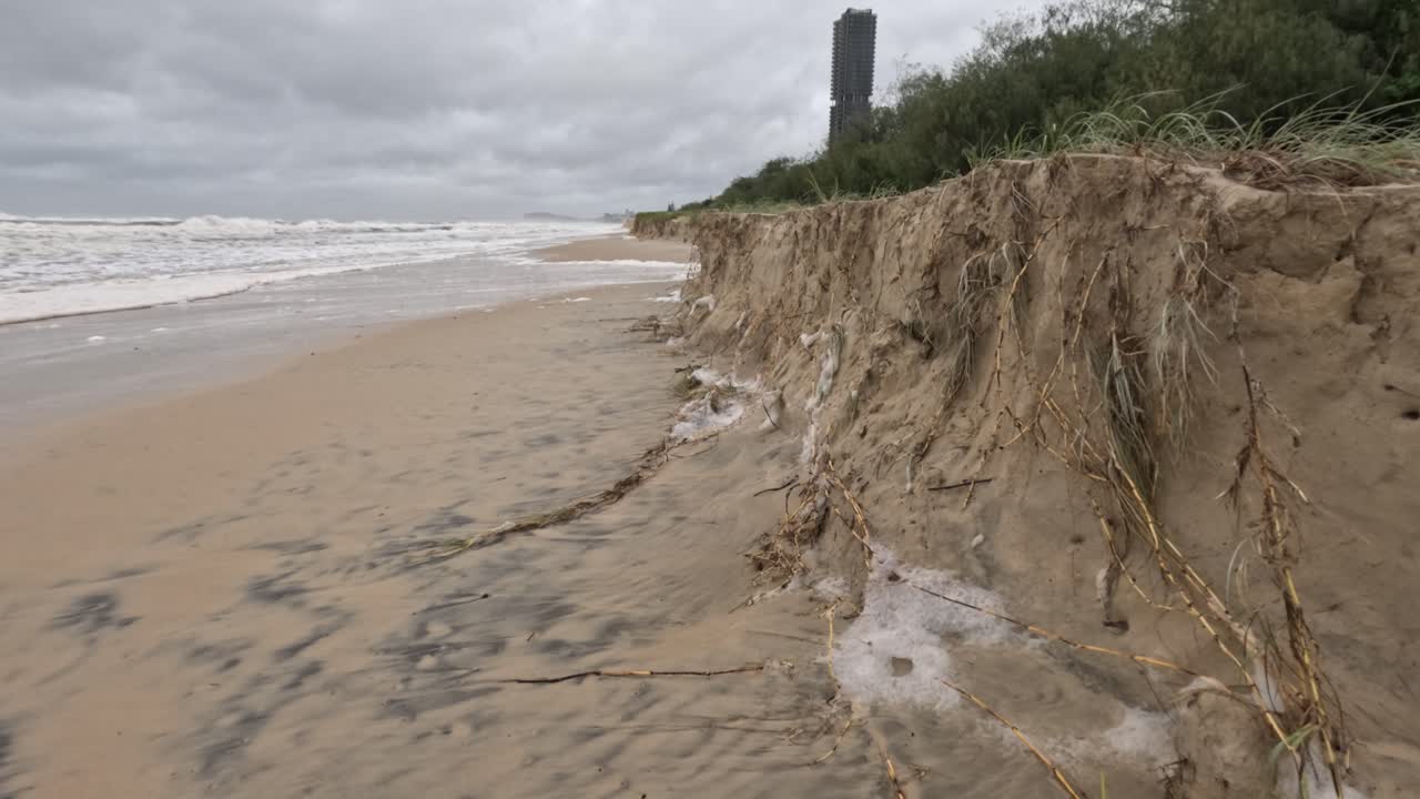бурная пляжная сцена показывает серьезные последствия эрозии и загрязнения во время циклона альфред, подчеркивая воздействие на окружающую среду и процессы выветривания