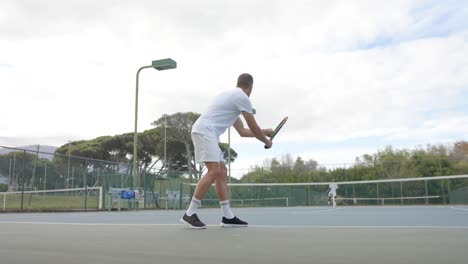 caucasian male tennis player serving ball to opponent on outdoor tennis court in slow motion