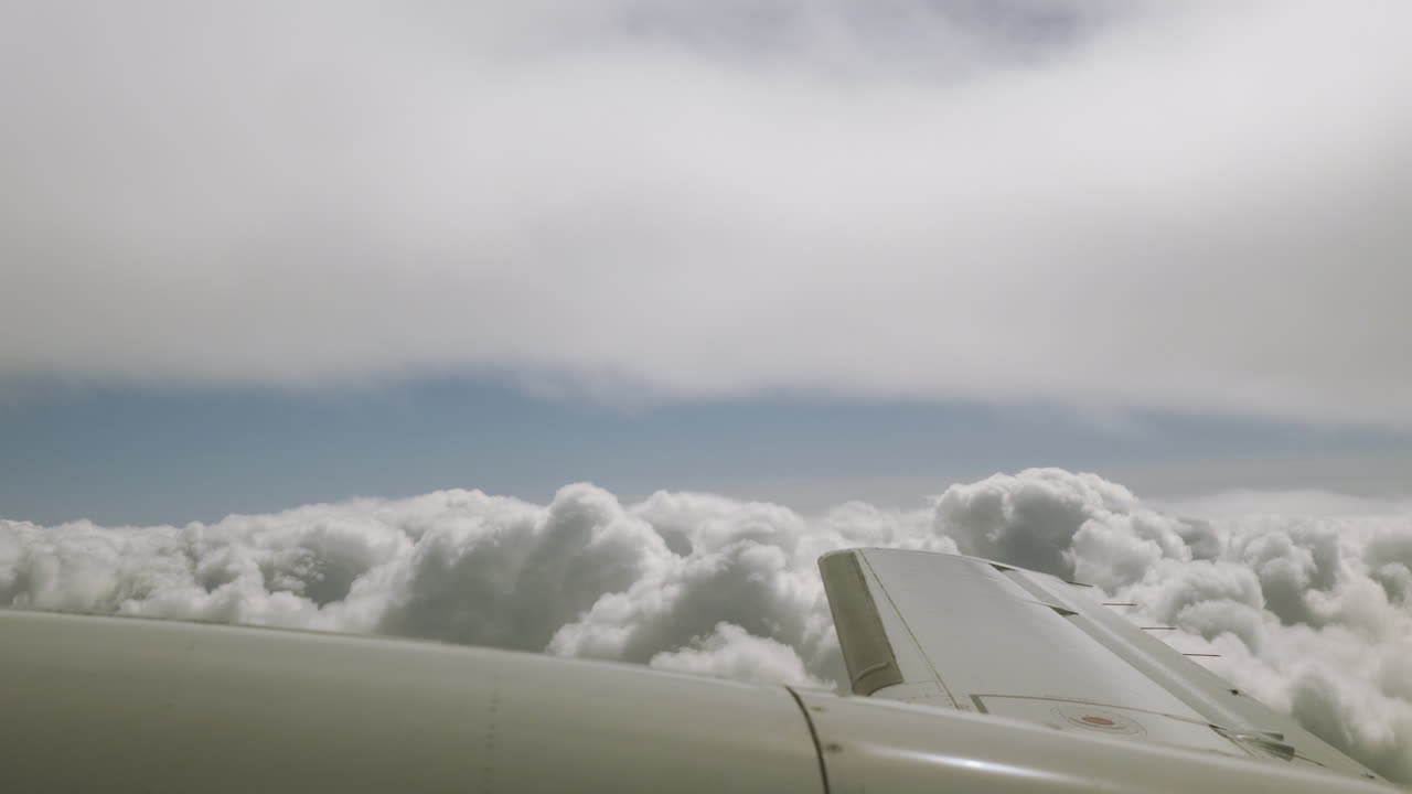 и крыло двигателя небольшого самолета, парящего по голубому небу с толстыми пушистыми облаками
