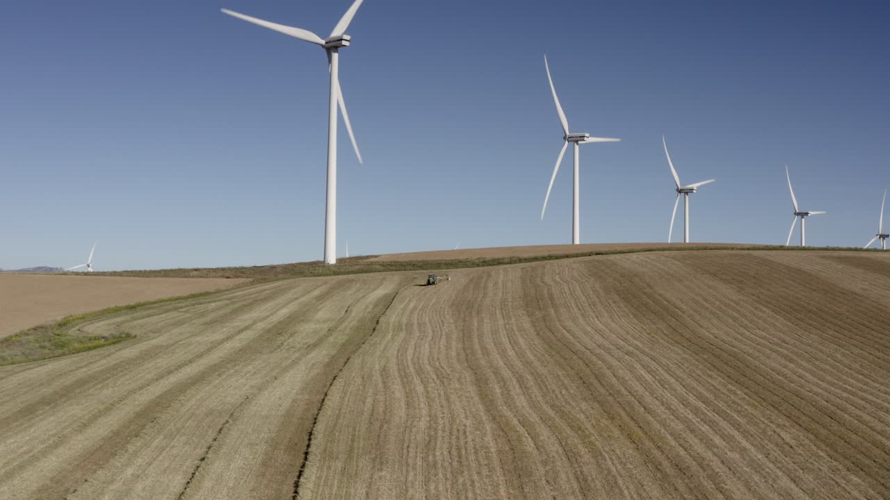Wind Farm and Tractor on a Hilly Farmland
