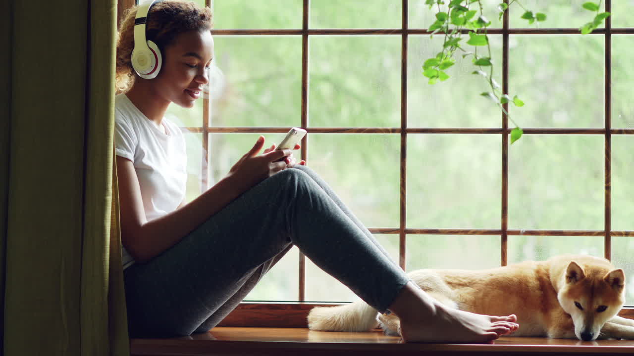Teen Girl with Headphones and Phone on Window Sill with Dog