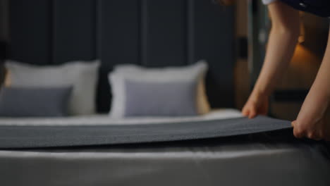 una criada de hotel hace la cama en una habitación de hotel de lujo.