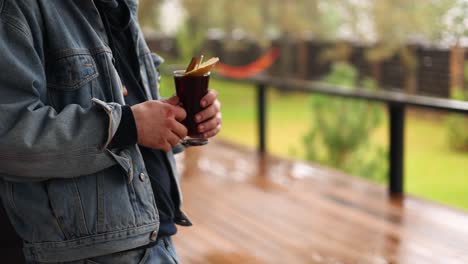 person holding a glass of mulled wine outdoors on a patio