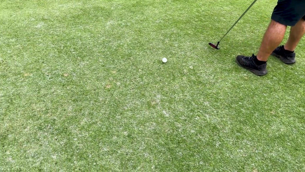 Golfista v černých teniskách mine krátký pat na greenu v Manile
