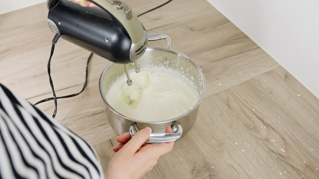 Mixing mascarpone into cream with electric mixer during tiramisu preparation