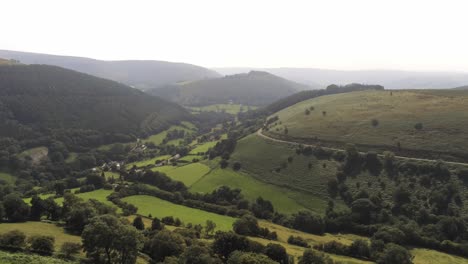 Vista-Aérea-Hacia-Atrás-Paso-De-Herradura-Exuberante-Paisaje-Brumoso-Valle-De-Montaña-Pintoresco-Paisaje-Rural