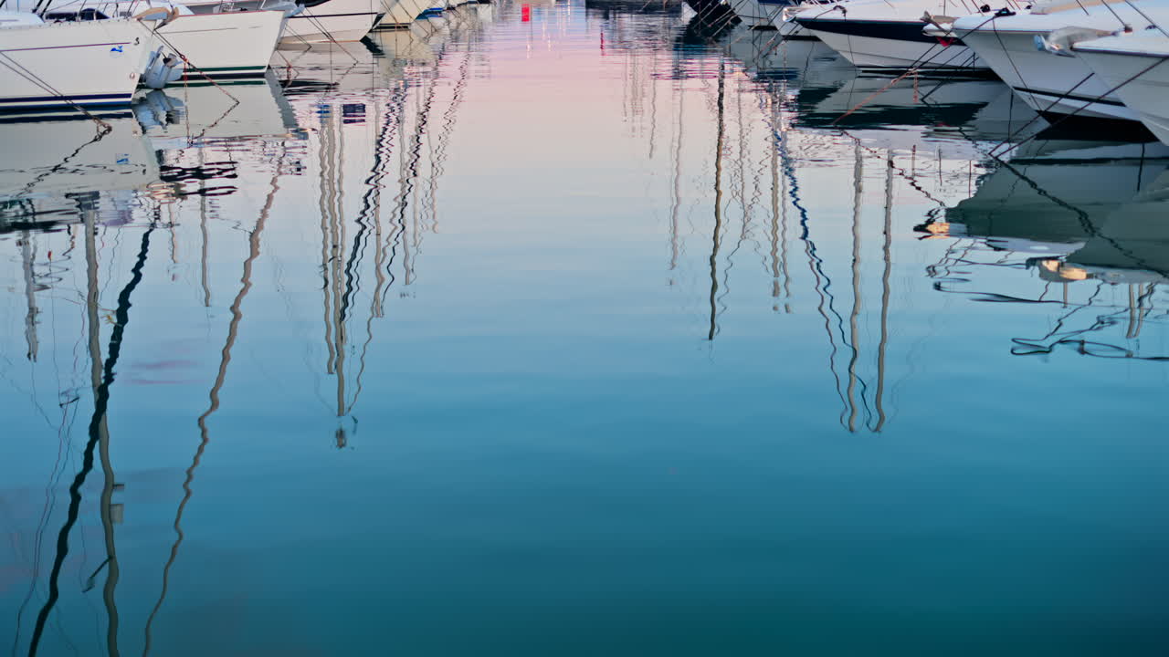 Reflections on the sea of white boats docked in the Port Vauban at sunset in Antibes, France