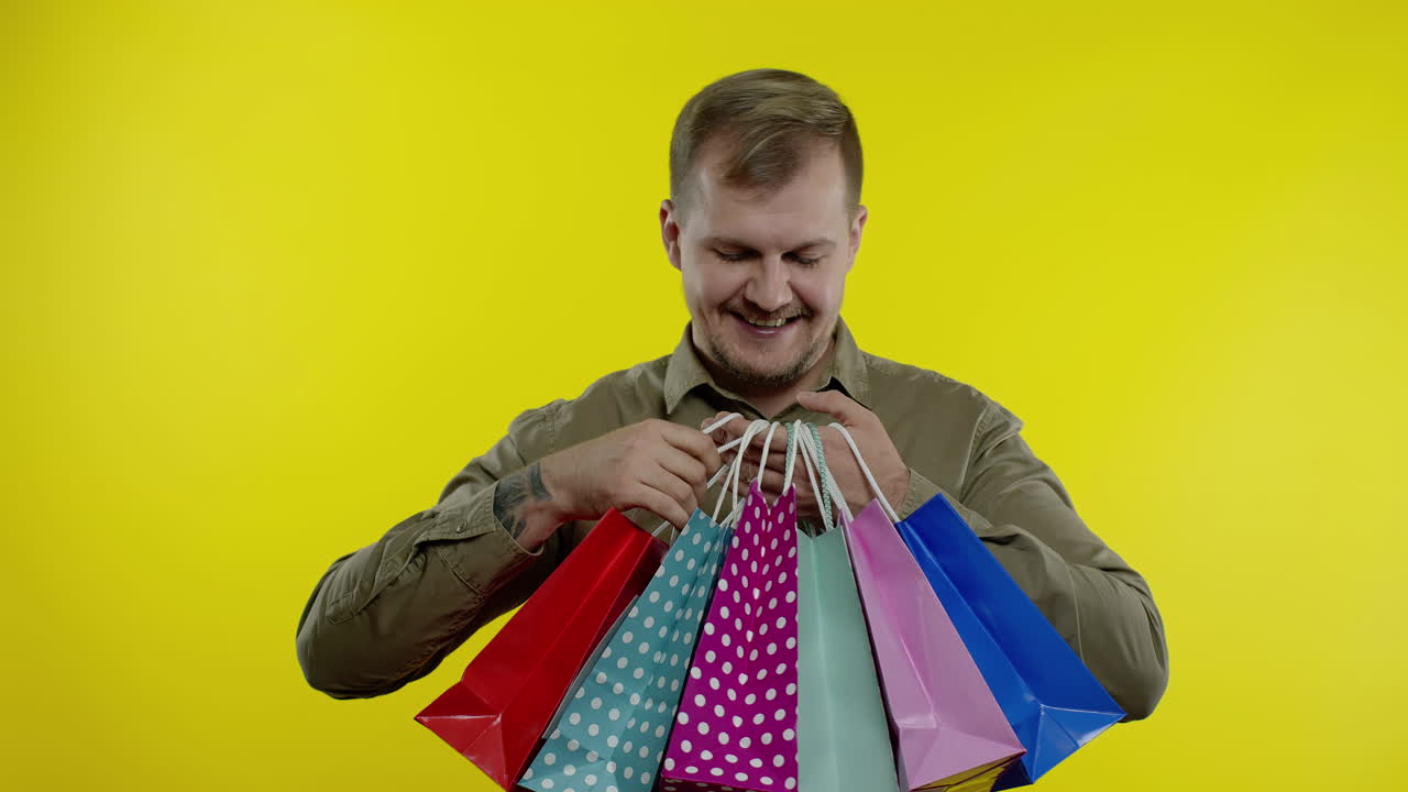 hombre mostrando la inscripción de black friday en las bolsas de compras, sonriendo, satisfecho con las compras a bajos precios