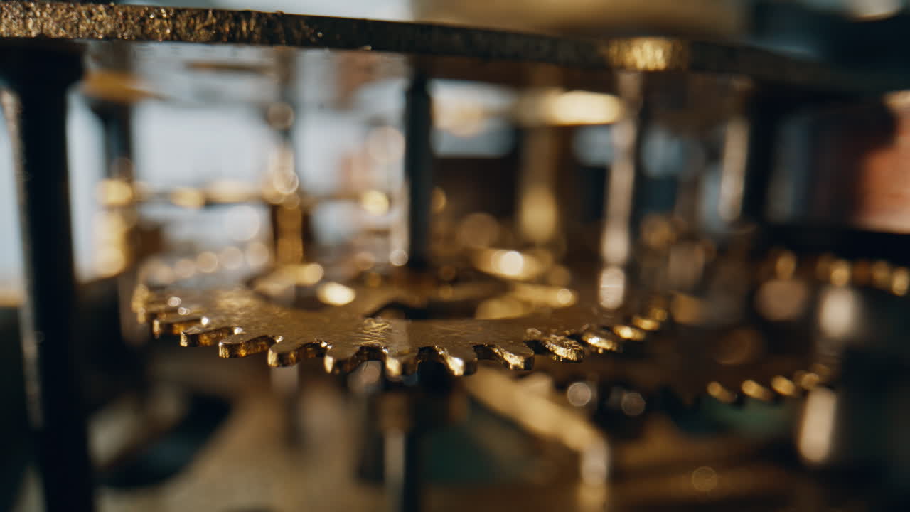 Macro cogwheels moving inside old mechanism placed on workbench. Gears spin