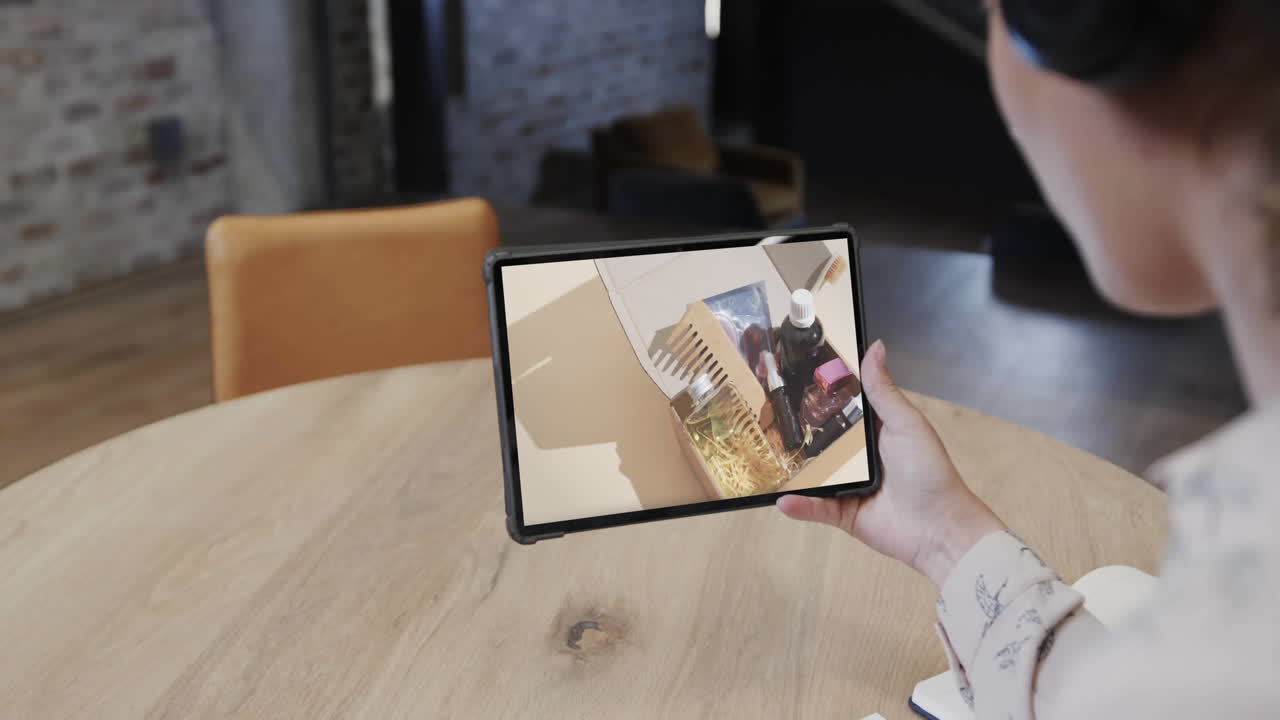mujer biracial usando tableta en un café comprando productos de belleza en línea, cámara lenta