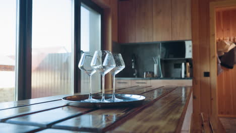 cozy cabin kitchen interior with wood walls, cabinets, bench dining table, microwave, kettle, stone fireplace, sliding glass door pouring natural daylight, showcasing modern rustic design harmony
