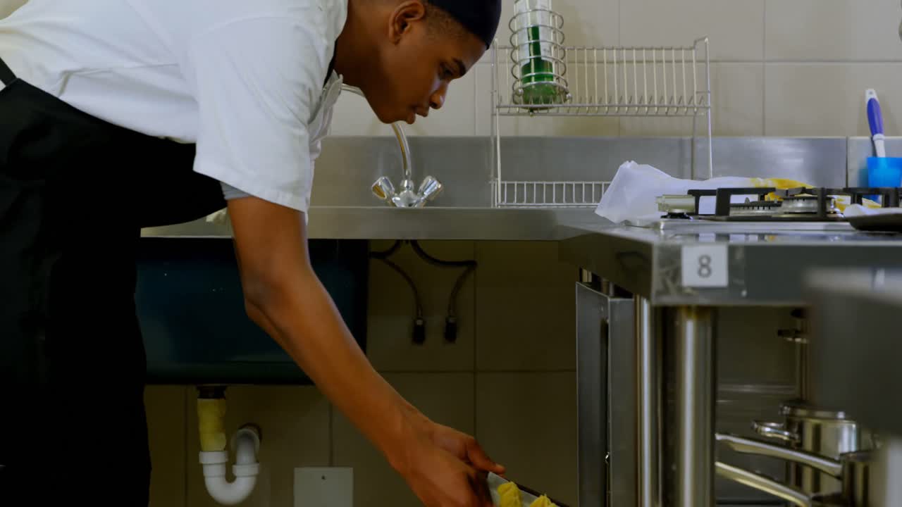 Chef putting tray of cookies in oven 4k