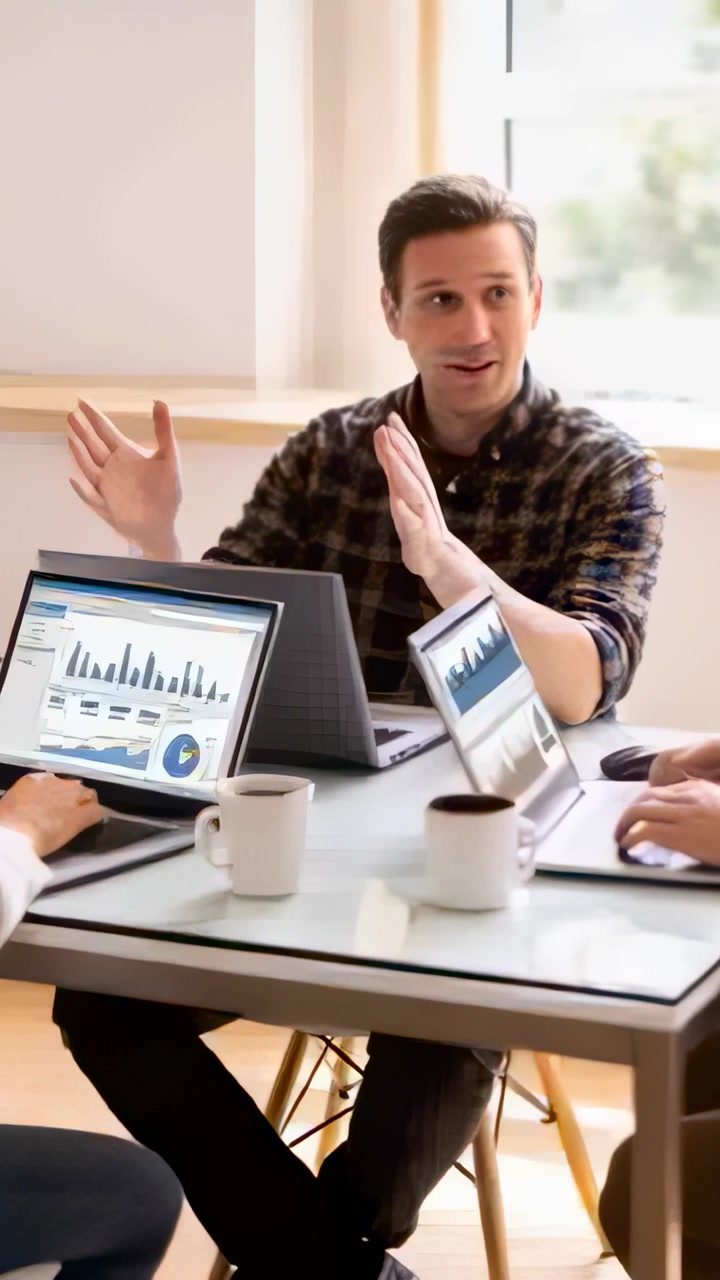 Vertical video: Starting man in plaid shirt presenting, gesturing and ending at table with laptops