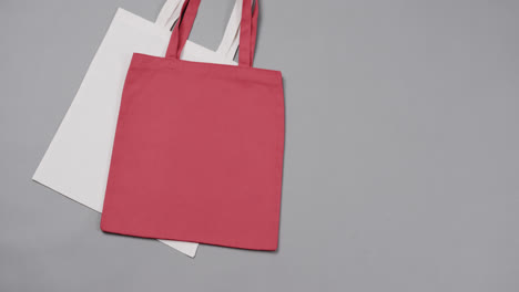 Close-up-of-white-and-red-bags-on-grey-background,-with-copy-space,-slow-motion