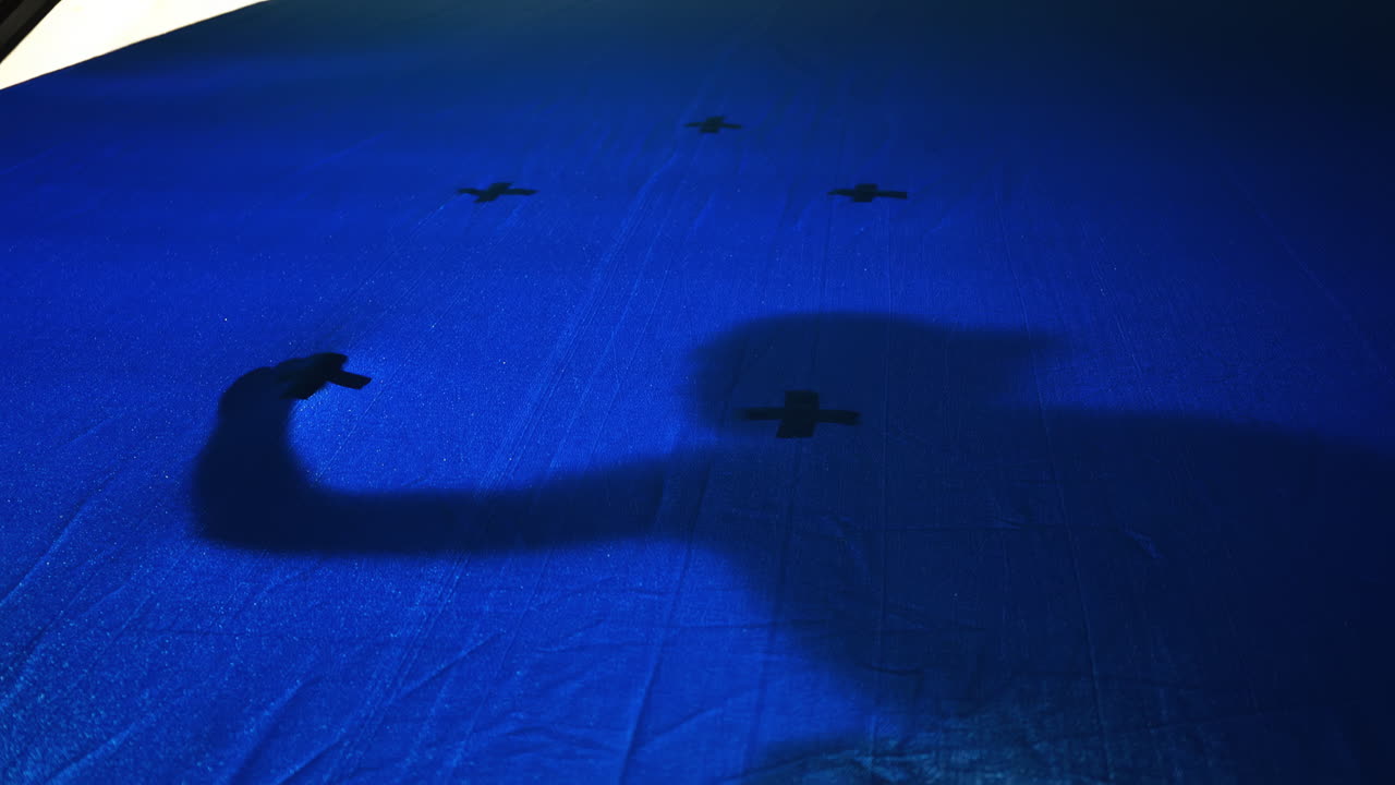 Red tracking markers on a chromakey with a man's shadow in a pose on it, movie set