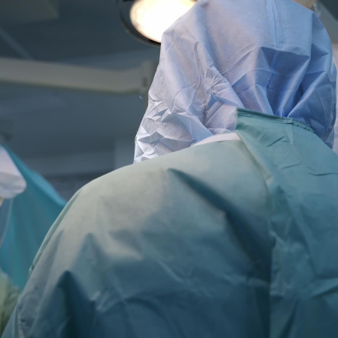 Busy surgeons at trauma operation. Doctors' team in protective suits stand around the operational table