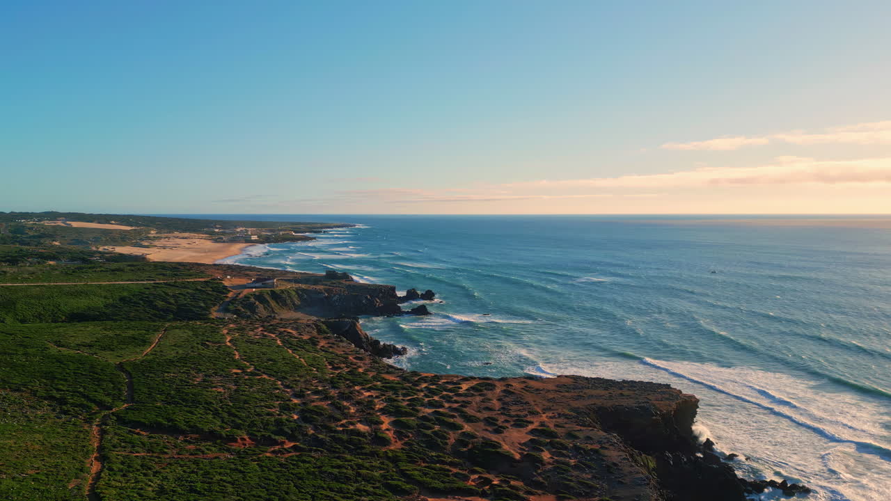 drones naturaleza costera día soleado. olas azules del mar salpicando la costa de vegetación baja
